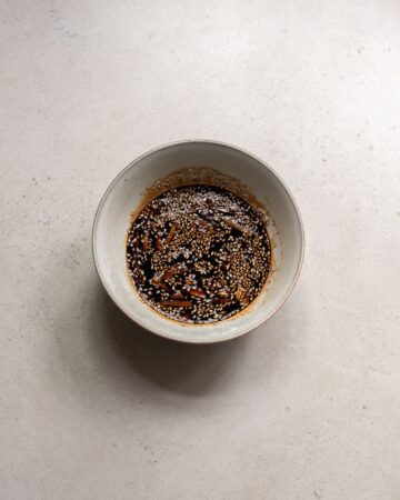 A mixing bowl with soy, ginger, and spices to go on baked chicken and vegetables for a sheetpan dinner.