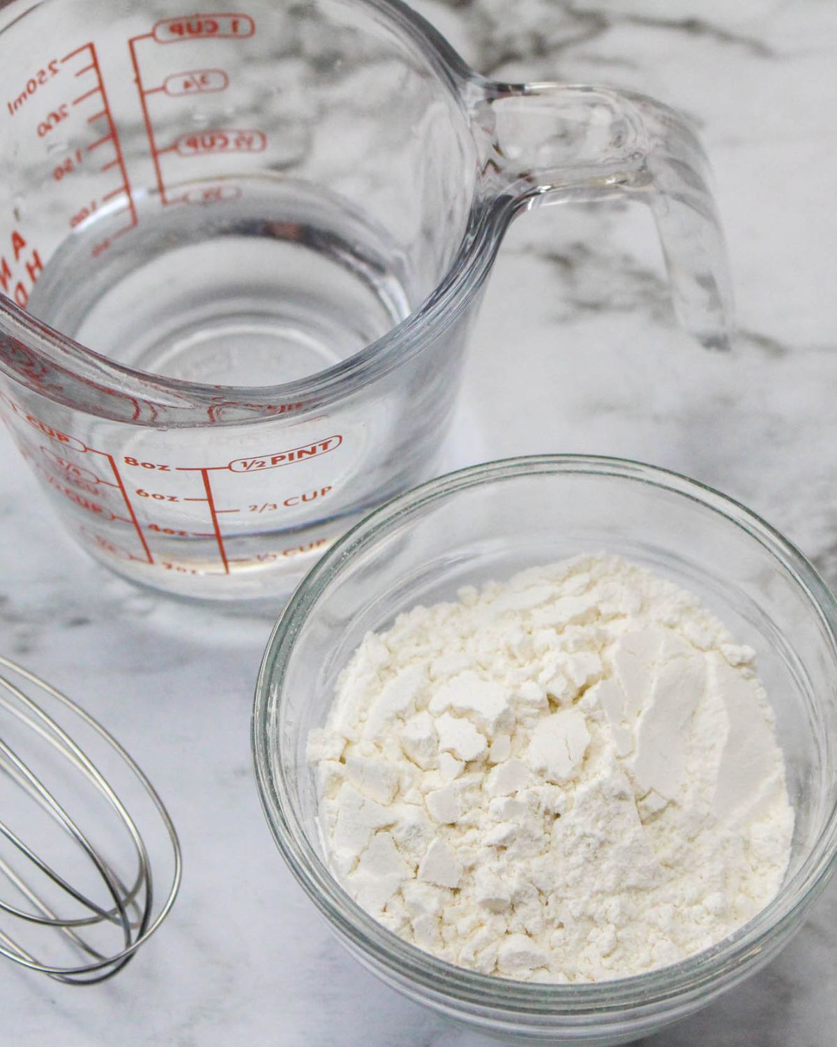 All purpose flour in a bowl and water in a measuring cup will be mixed together to make a broccoli cheddar soup for a thickening agent.