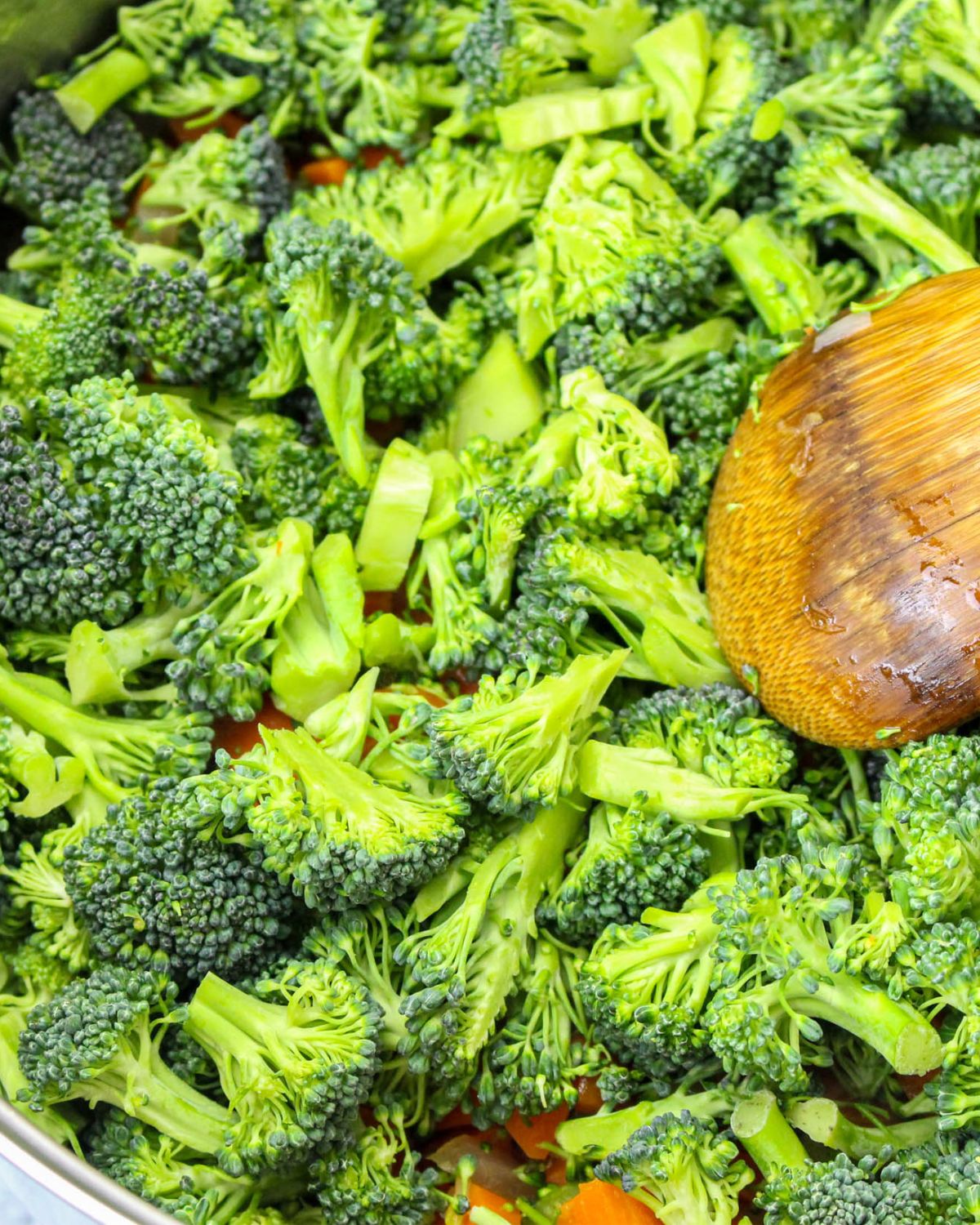 Fresh broccoli in a pot with diced carrots and onions to make a broccoli beer cheese soup.