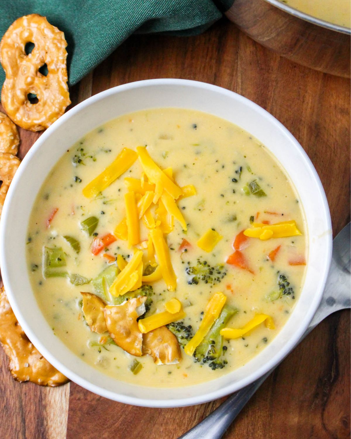 An overhead view of a white bowl with a creamy broccoli soup wth shredded cheddar cheese on top.