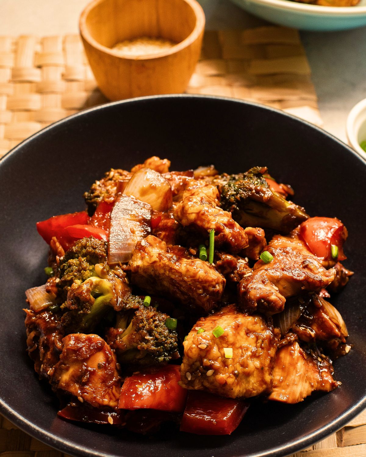 A black bowl with ginger soy chicken and vegetables made on a sheet pan.