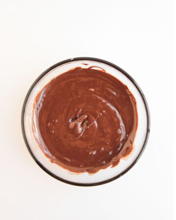 A glass bowl with melted chocolate in the bowl.