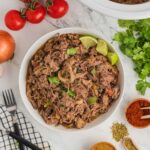 A large white bowl of shredded beef with Mexican flavors.