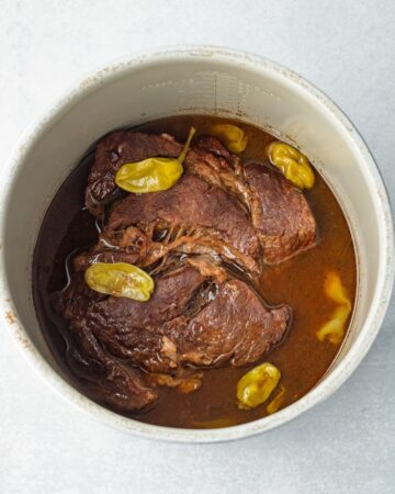 An Instant Pot vessel with a cooked Mississippi pot roast made in the Instant Pot.