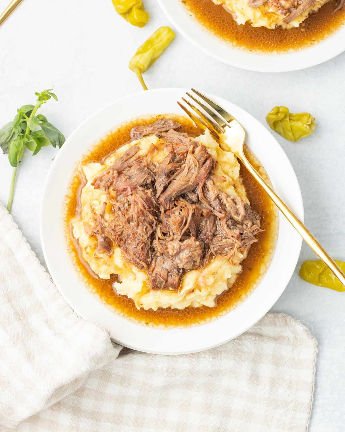 An overhead view of a plate of mashed potatoes topped with mississippi pot roast.