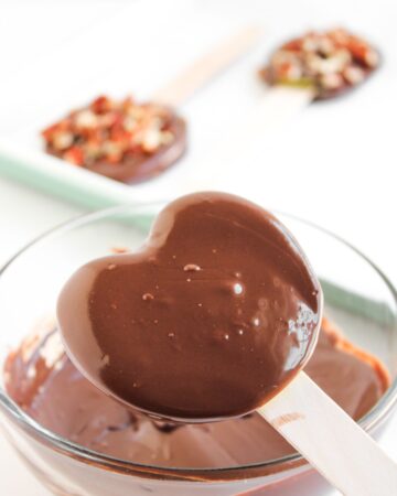 Apples dipped in chocolate to make Turtle apple pops.