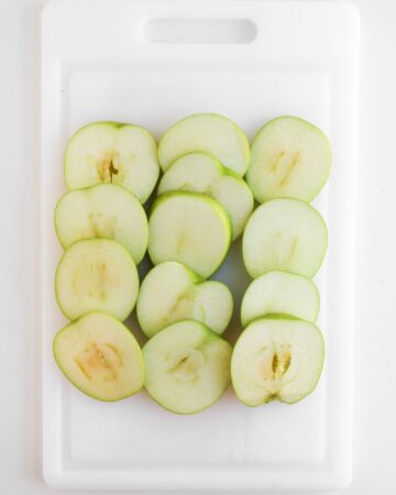 Apple Slices sliced to make apples on a stick drizzled with chocolate and pecans.