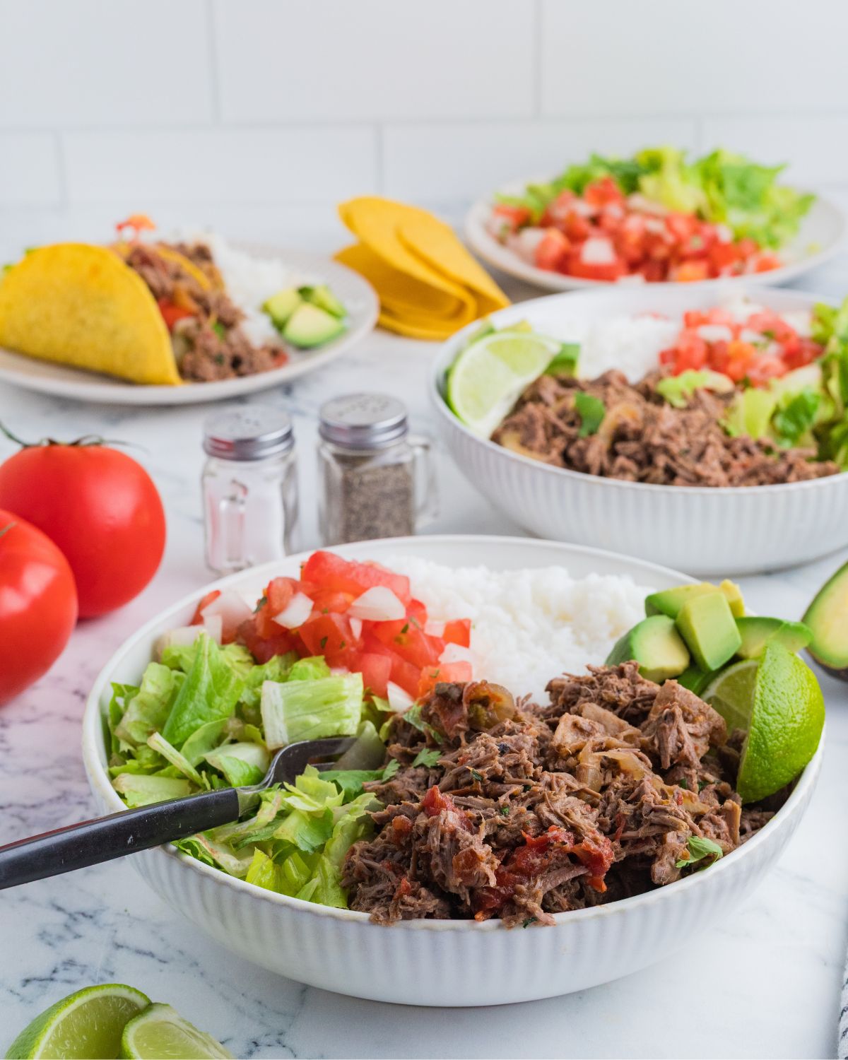 Shredded Mexican Beef in a bowl with rice, lettuce, and tomatoes.