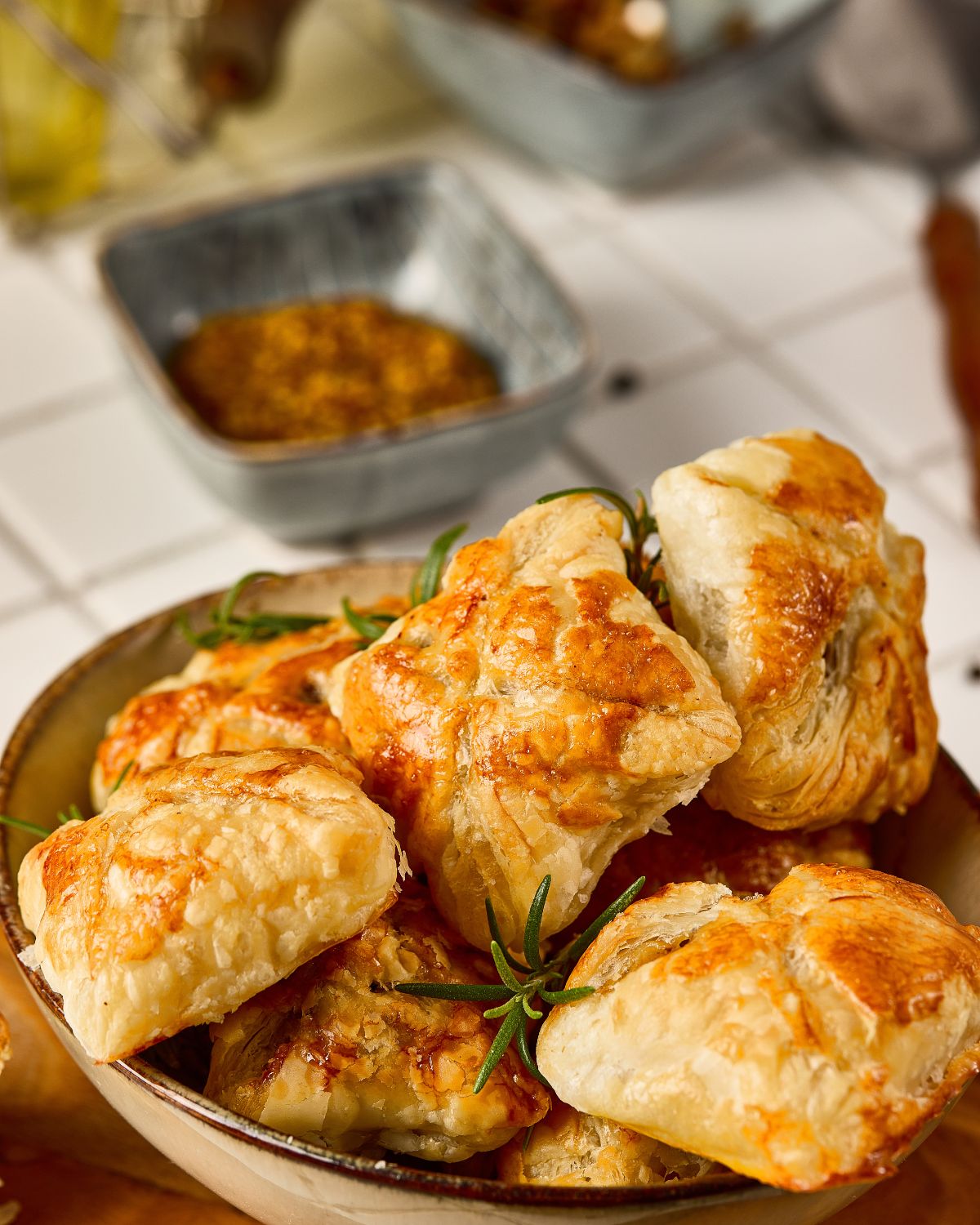 Beef Wellington Bites stacked on a plate with fresh rosemary. 