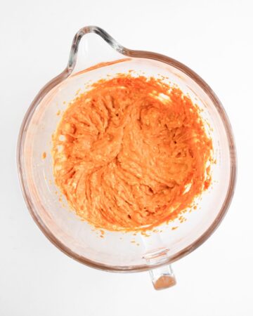 A glass measuring bowl with pumpkin puree to make pumpkin pie dip.