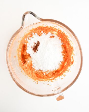 A glass measuring bowl with pumpkin puree and confectioner's sugar with vanilla extract to be mixed to make a quick pumpkin pie dip recipe.