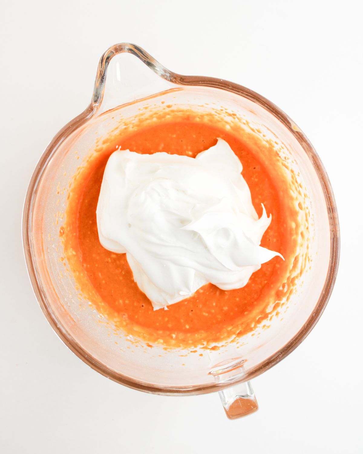 A glass measuring bowl with pumpkin pie dip ingredients being whipped with cool whip to make a pumpkin pie dip with cream cheese.