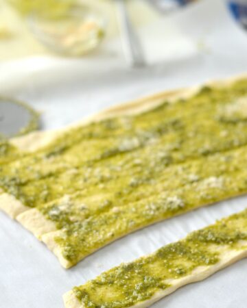 Crescent dough topped with Basil Pesto cut into strips to make Christmas Tree Appetizers.