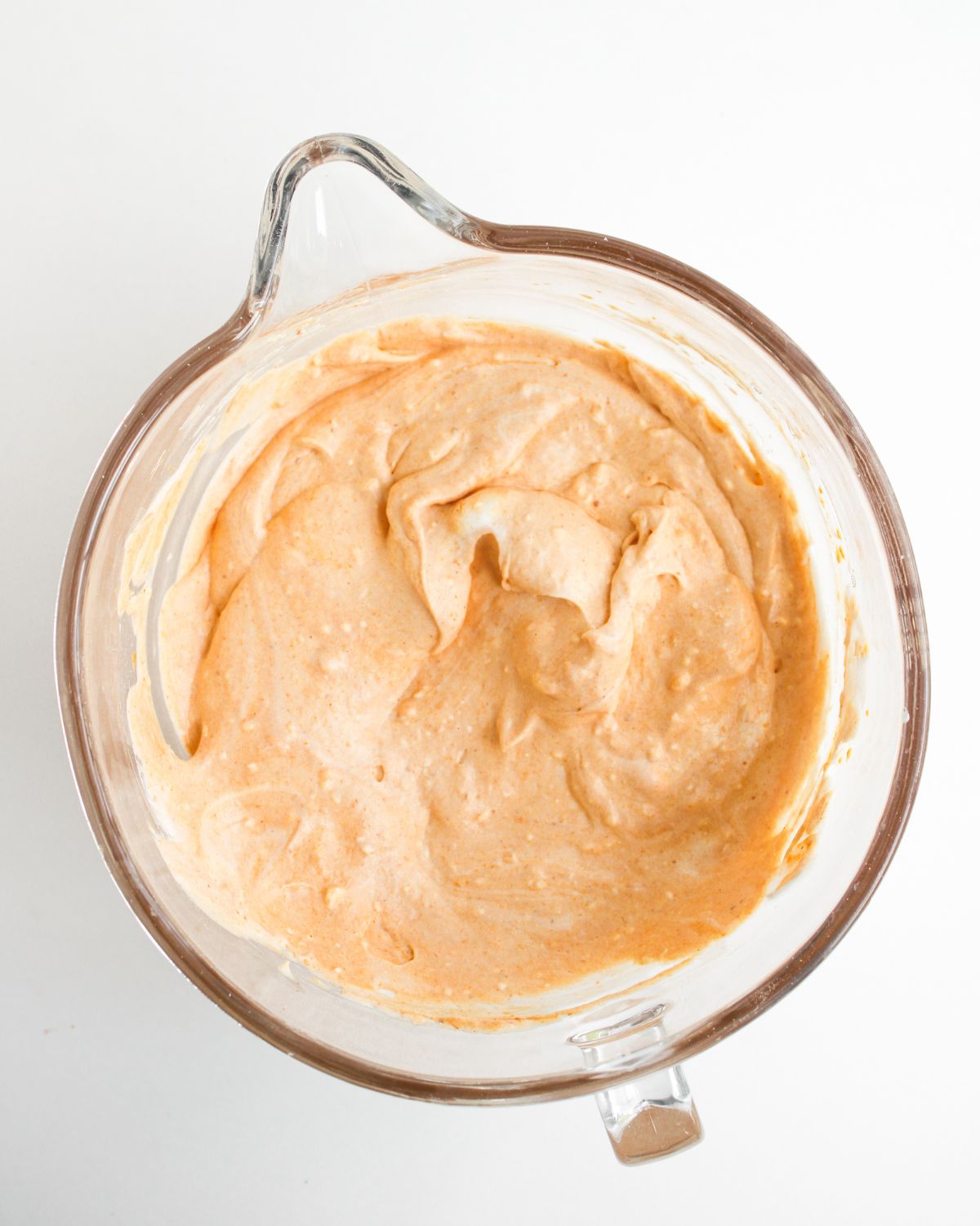 The ingredients for pumpkin pie dip mixed together in a glass measuring bowl.