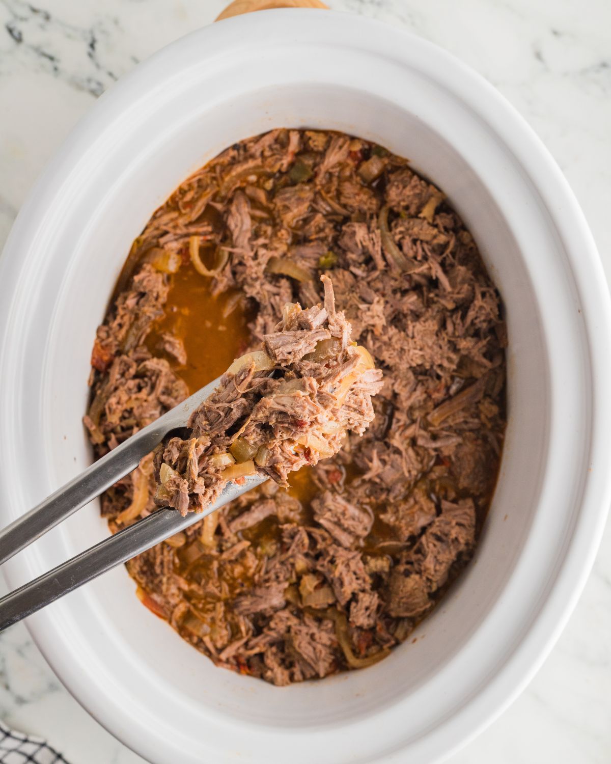 Slow cooker vessel with shredded beef with Mexican flavors.