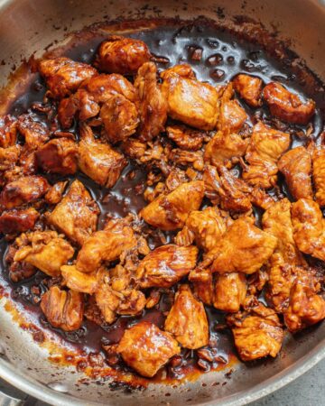 A skillet with chicken pieces in a homemade teriyaki sauce.