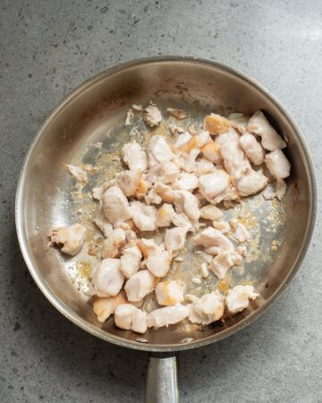 A saute pan with chicken thighs being sauteed to make homemade teriyaki chicken bowls with rice and vegetables.