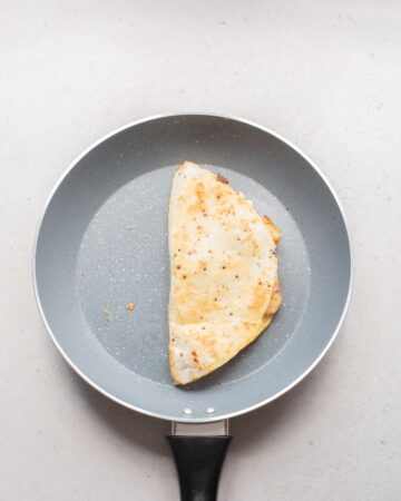 A shrimp quesadilla in a saute pan folded over.