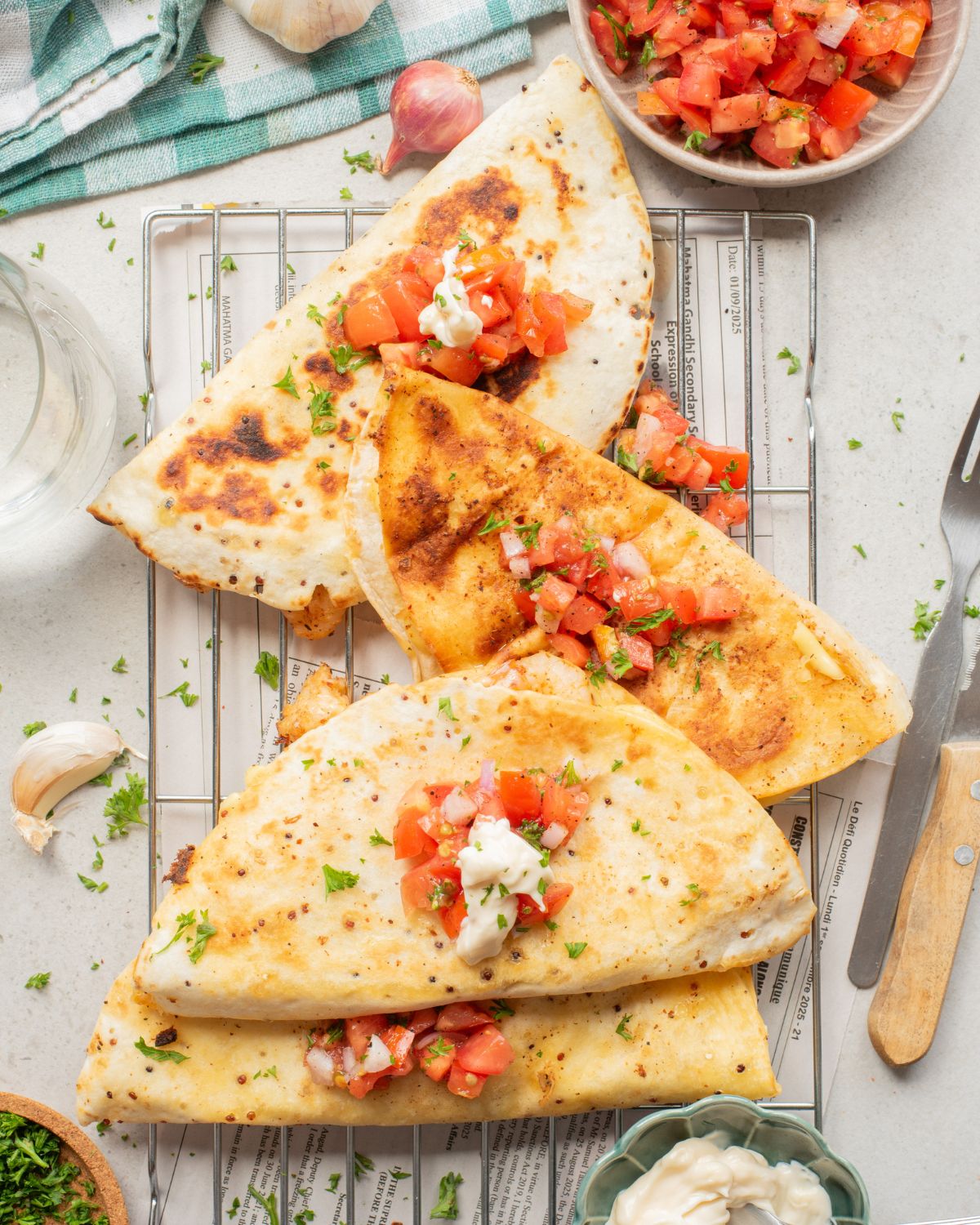 Shrimp quesadillas folded in half that have been cooked and topped with pico de gallo, sour cream, and fresh cilantro.