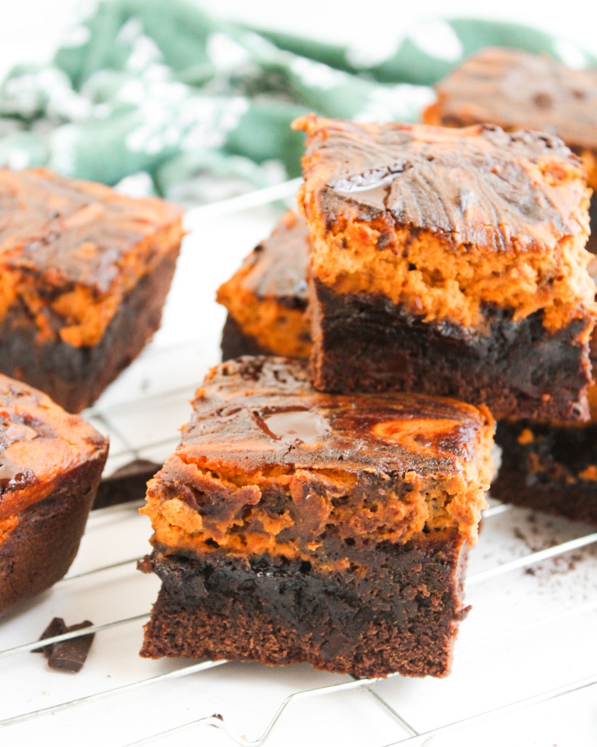 Pumpkin spice fudgy brownies with a creamy pumpkin swirl on a cooling rack.
