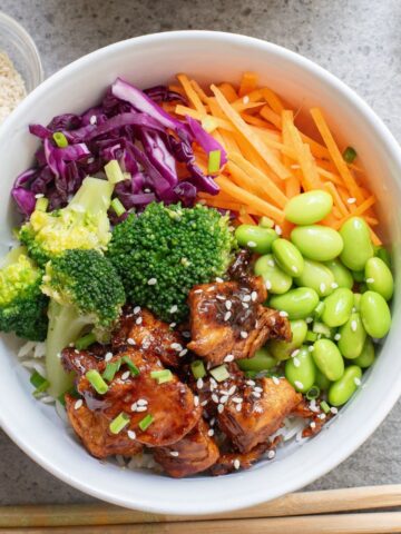 teriyaki chicken and rice bowl with veggies in a white bowl.