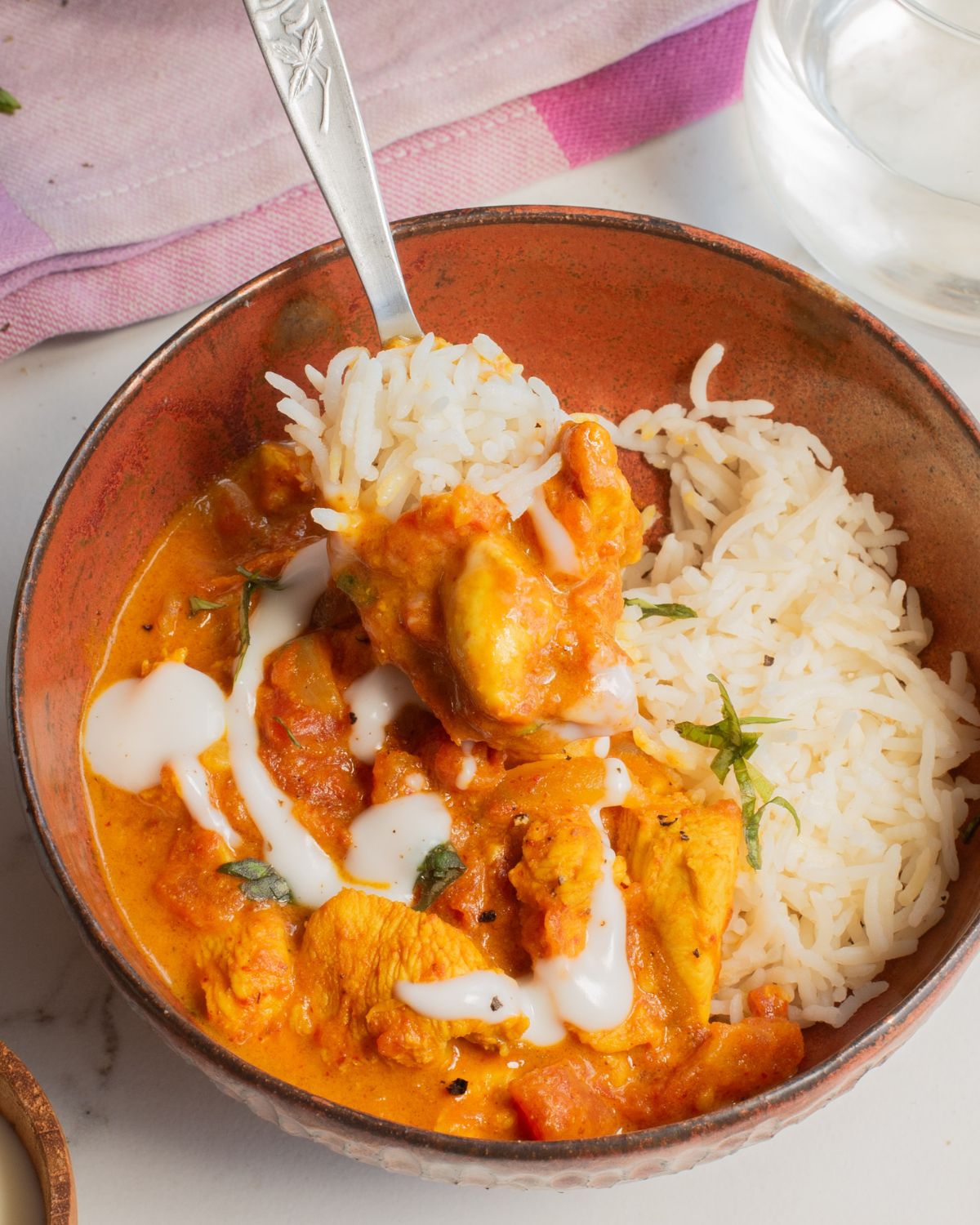 Simple butter chicken and basmati rice in a bowl being picked up with a fork.