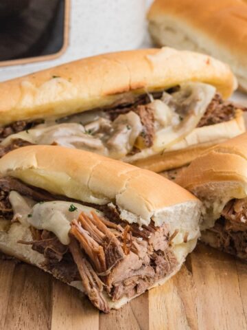 Shredded French dips on Hoagie Bread sitting on a cutting board.