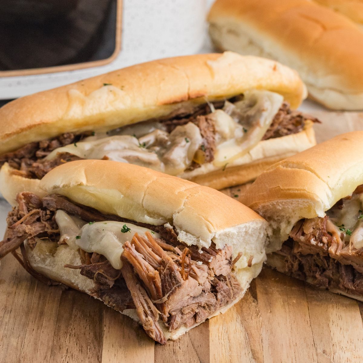 Shredded French dips on Hoagie Bread sitting on a cutting board.