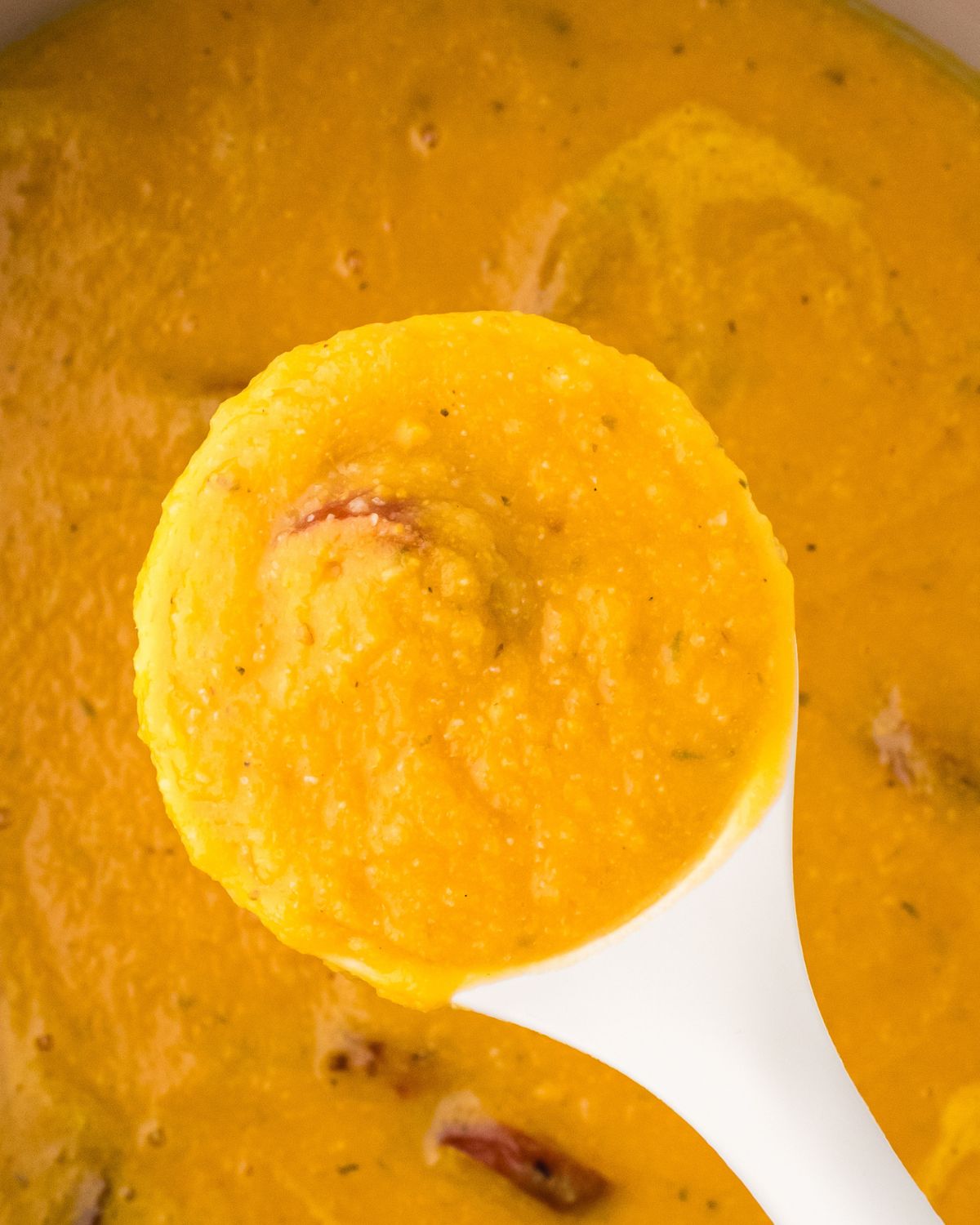 A bowl of homemade cauliflower sweet potato soup with a big spoonful being picked up. 