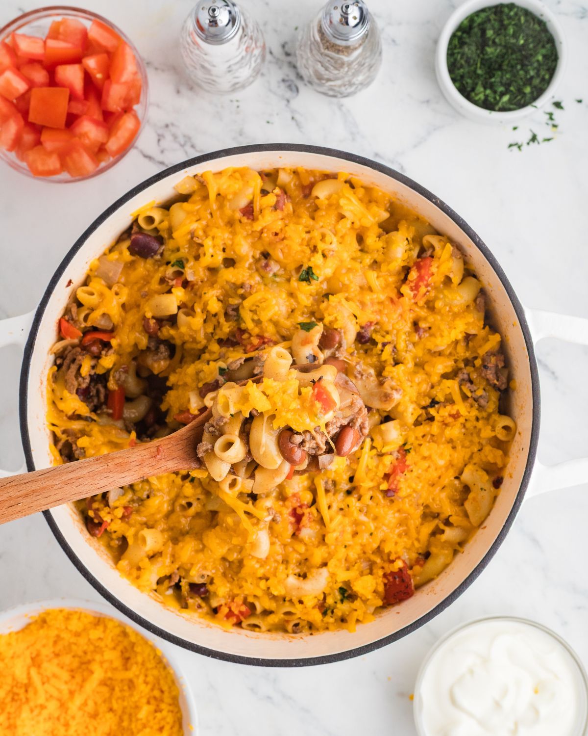 Chili and cheese mac and cheese topped with cheddar cheese in a Dutch oven.