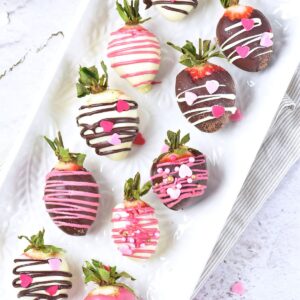 Valentines day chocolate covered strawberries with a pink drizzle and heart sprinkles.