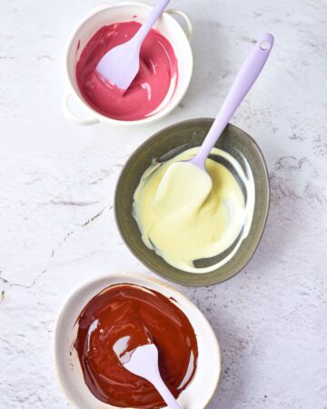 Three bowls with melted chocolate to make the toppings for chocolate covered strawberries.