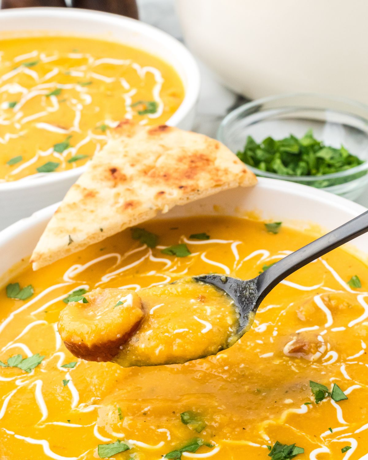 Creamy cauliflower soup with andouille sausage being picked up on a spoon.