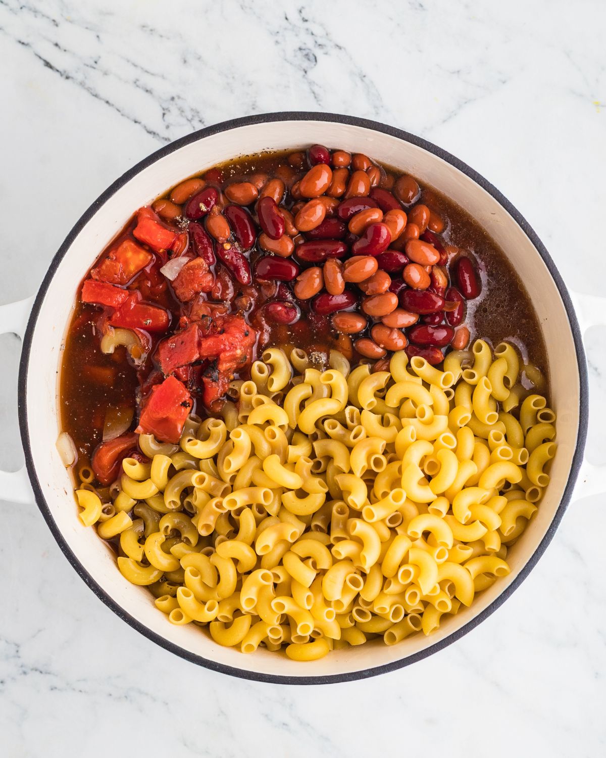 Elbow macaroni, roasted diced tomatoes, seasonings, and chili beans to make chili and mac and cheese recipe.