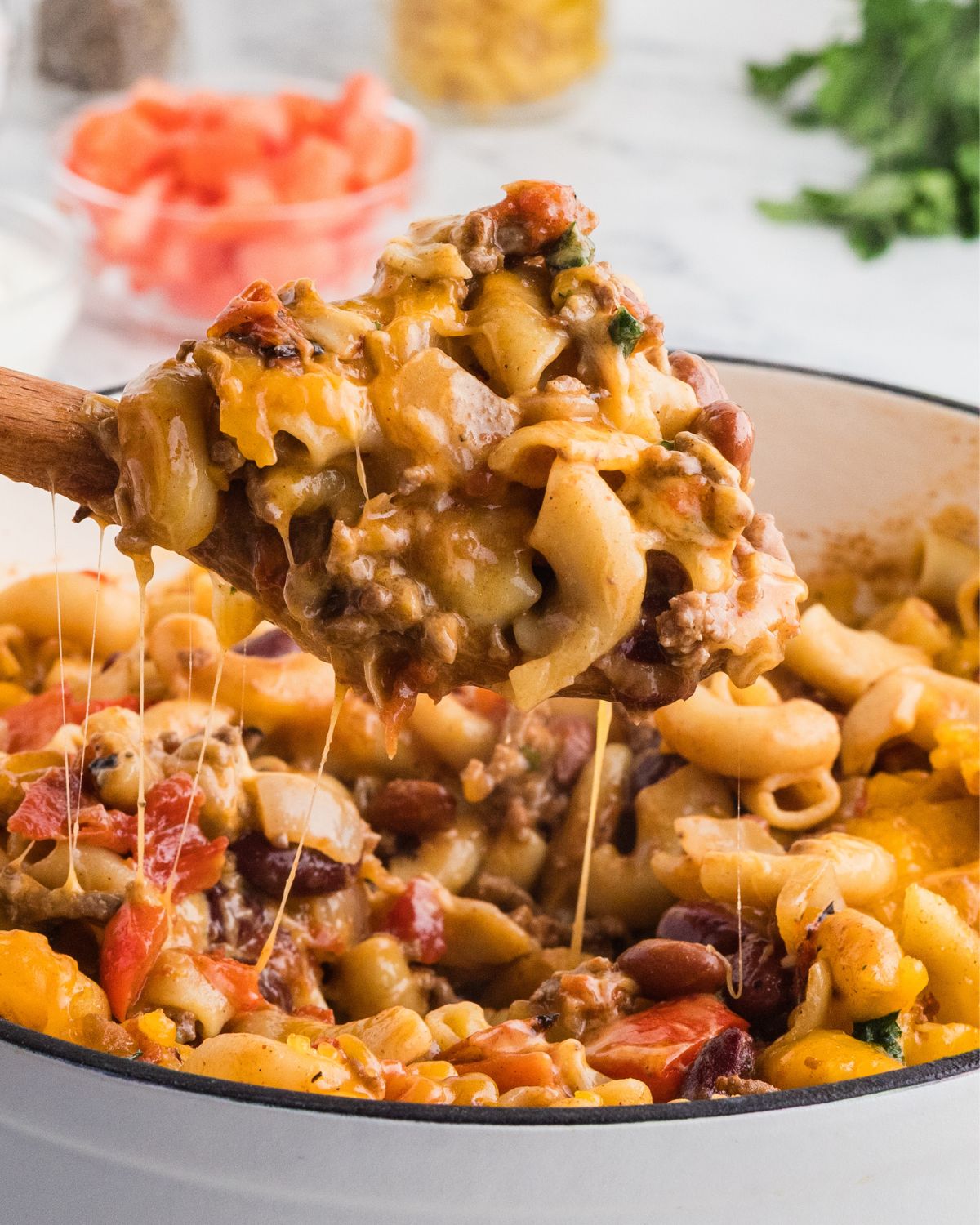 Macaroni and cheese chili mac and cheese being picked up out a Dutch oven.