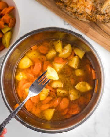 An instant pot vessel with potatoes and carrots made for an instant pot pork dinner.