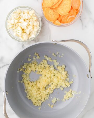 A soup pot with onions saut&eacute;ing to make a cauliflower and sweet potato soup.