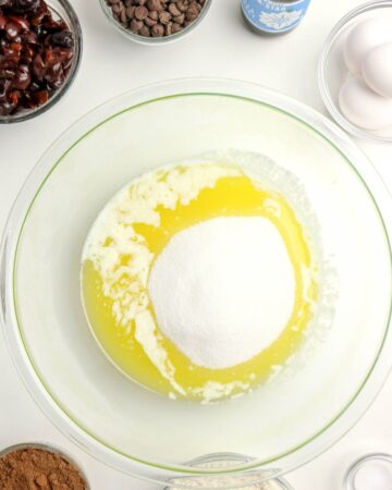 A glass bowl with melted butter and sugar to make cherry brownies.