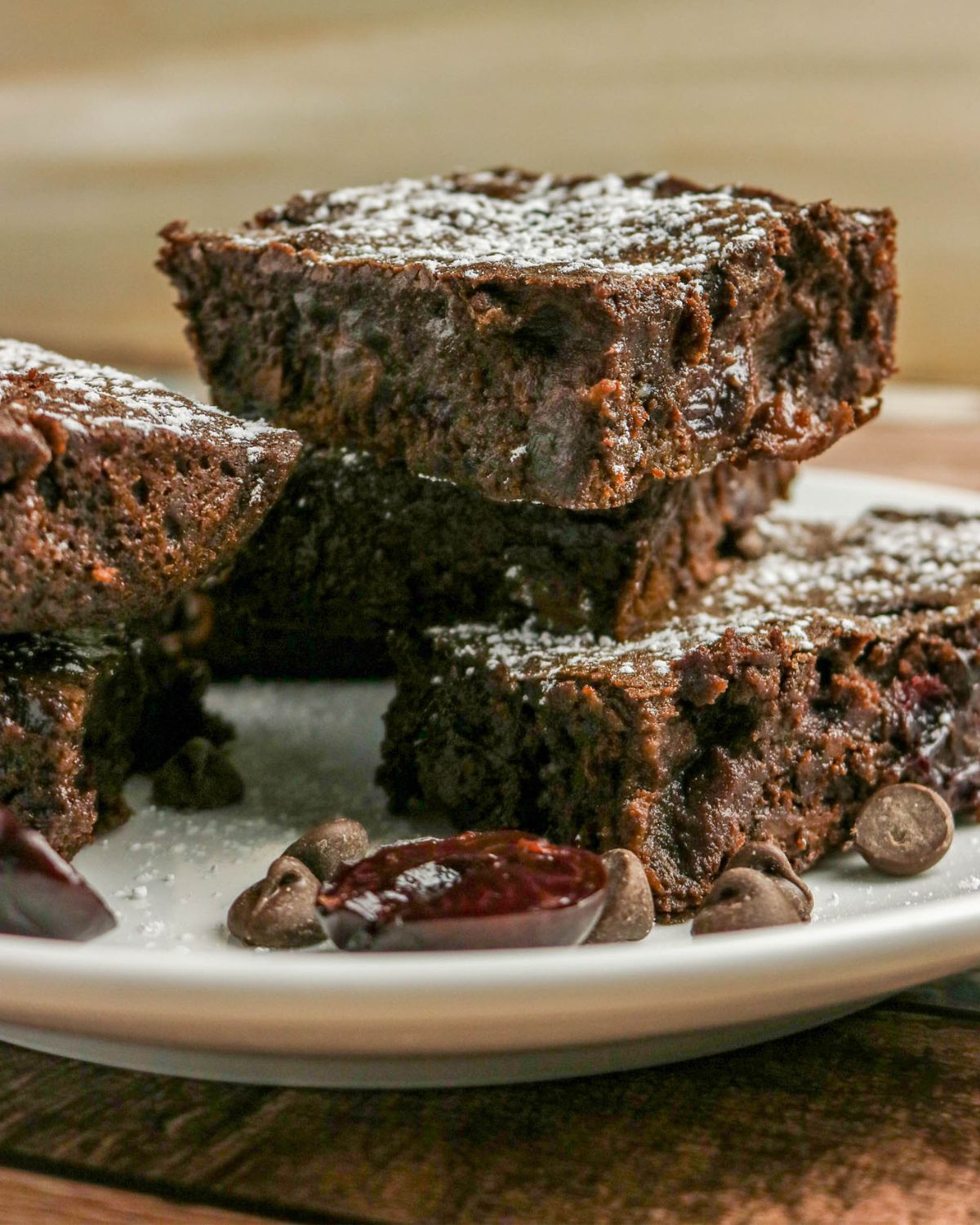 Homemade cherry chocolate brownies stacked on a plate.
