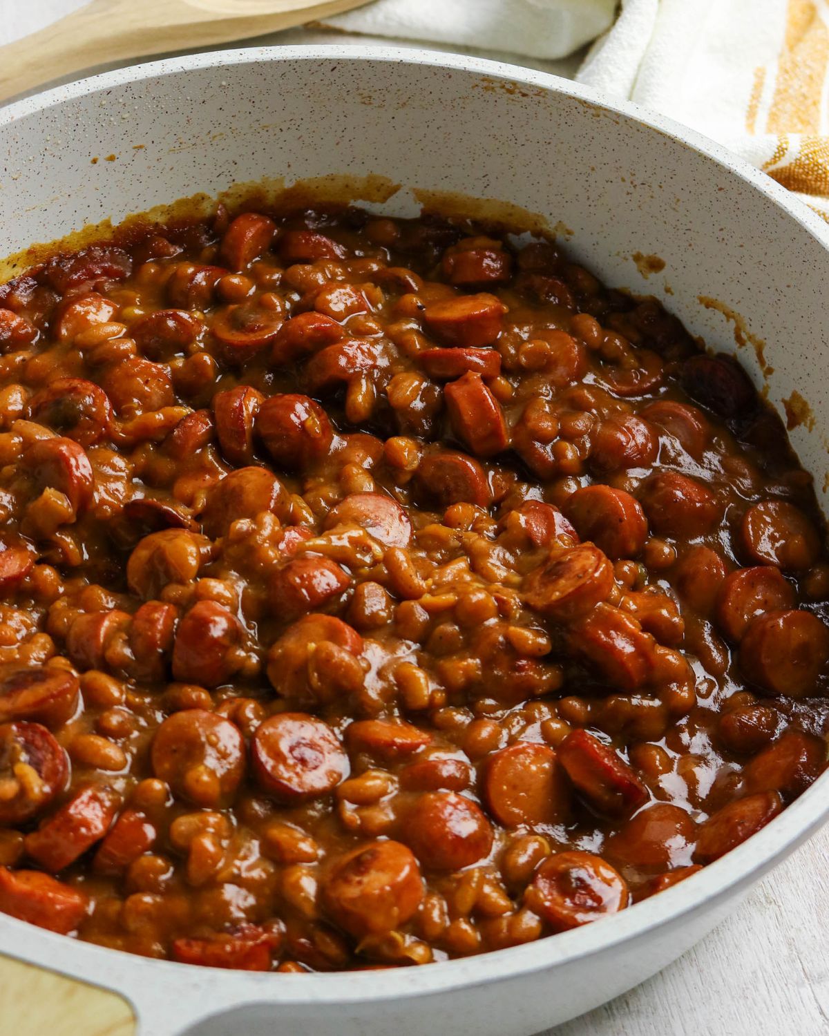 Beans and hot dog slices in a large skillet to make homemade beanie weenies.