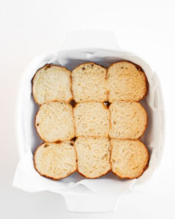 A baking tray with the bottom of breakfast sliders to make egg, bacon, sausage, and cheese breakfast sliders.