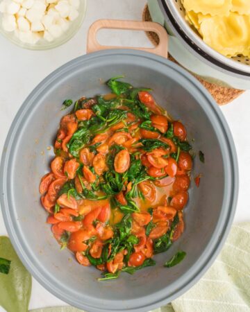 Tomatoes and basil in a large pot to make Caprese Ravioli. 