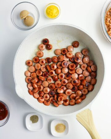 Sliced hot dogs in a pan to make beanie weenies. 