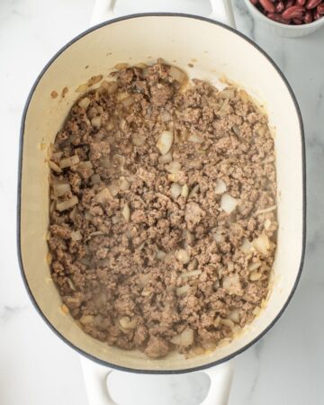 A Dutch oven with onions and ground beef saut&eacute;d to make Pasta e Fagiole.