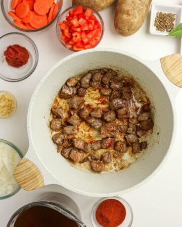A large pan with seared seasoned beef to make Hungarian Goulash.