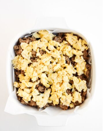 A slider breakfast sandwich being made with sausage and eggs.