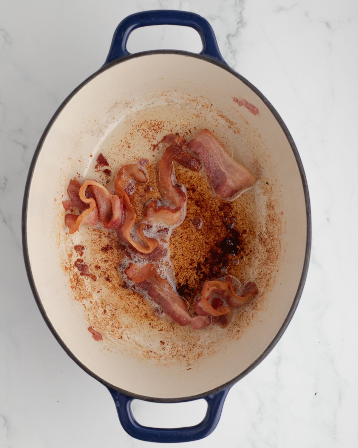 A dutch oven with bacon being browned for Manhattan Clam Chowder.