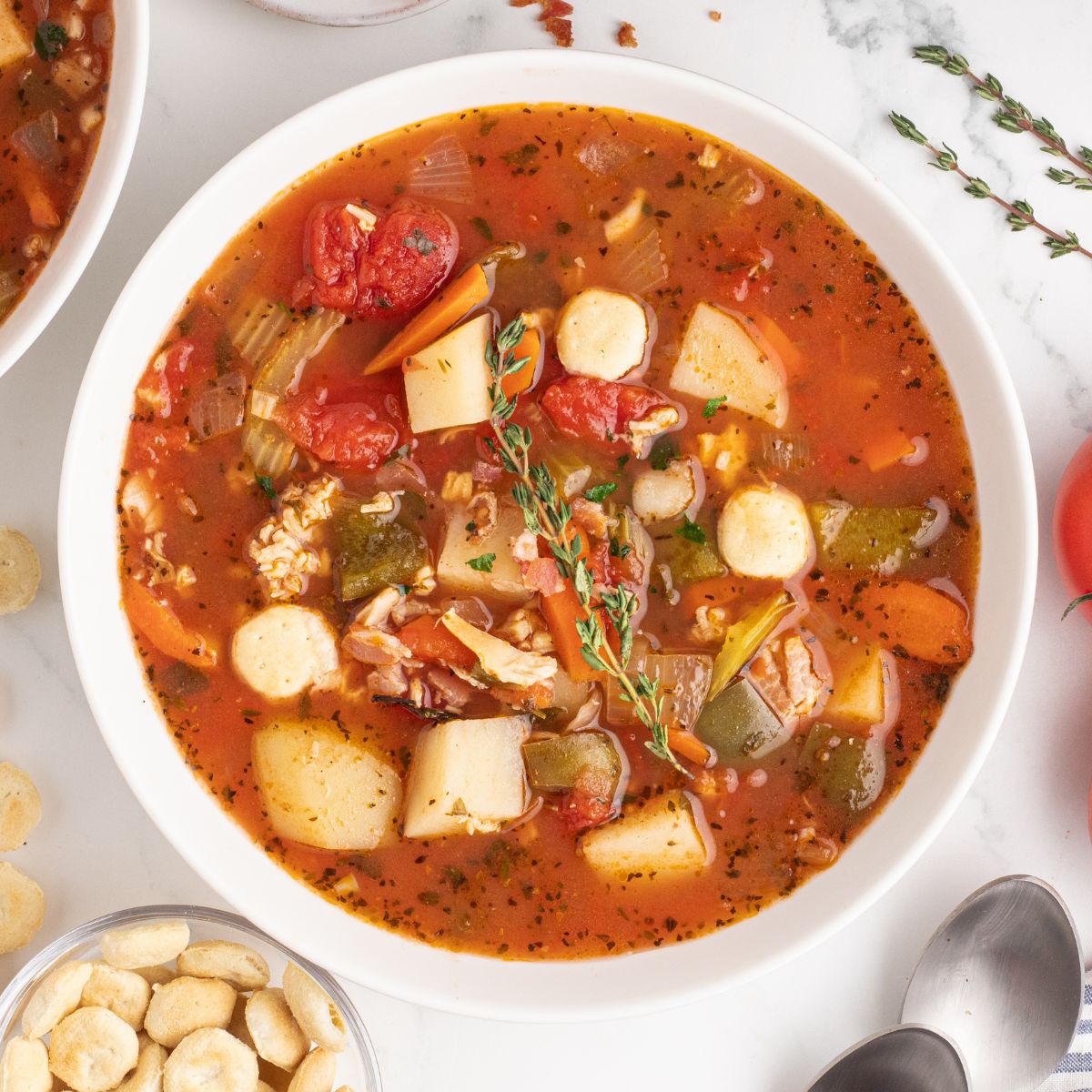 Manhattan Clam Chowder in a bowl topped with a sprig of fresh thyme.