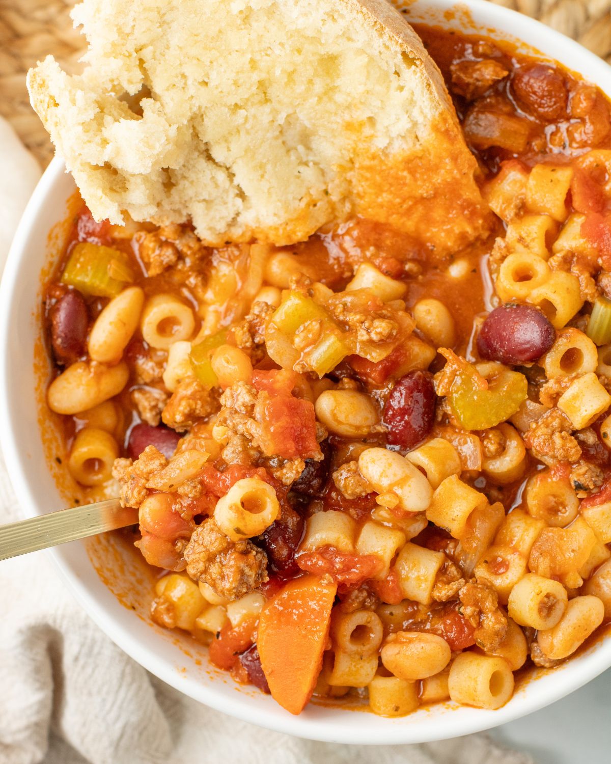 A bowl of pasta fazool with a slice of Italian bread.