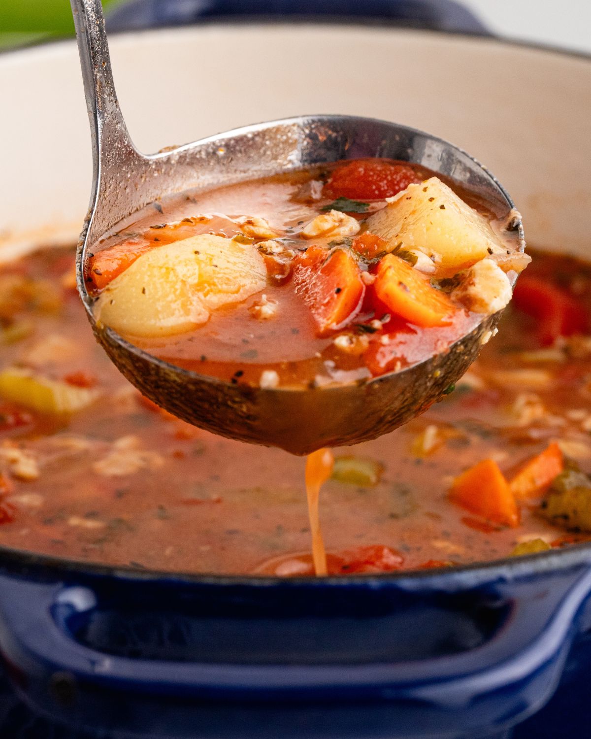 A soup ladle picking up Manhattan clam chowder out of the Dutch Oven.